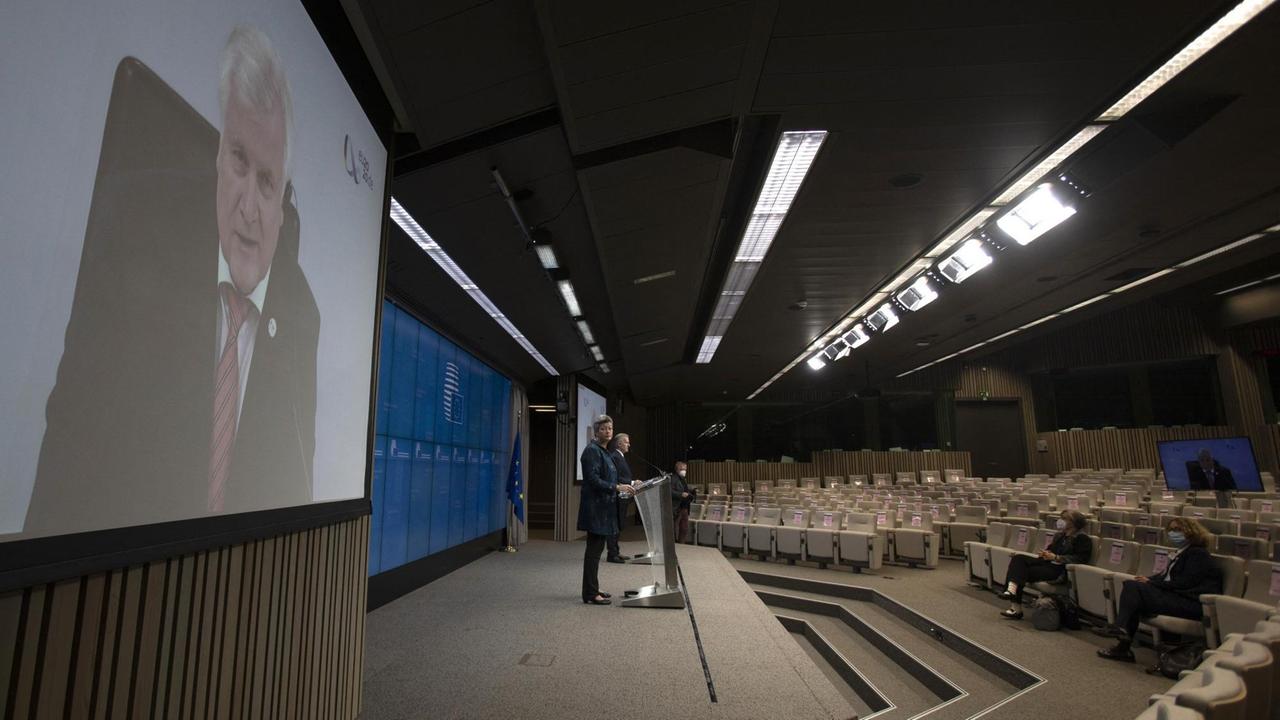 Ein Live-Stream von Horst Seehofers Rede wird in einem fast leeren Auditorium an die Wand projiziert.