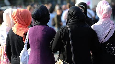 Fünf Frauen mit Kopftüchern, von hinten fotografiert. 