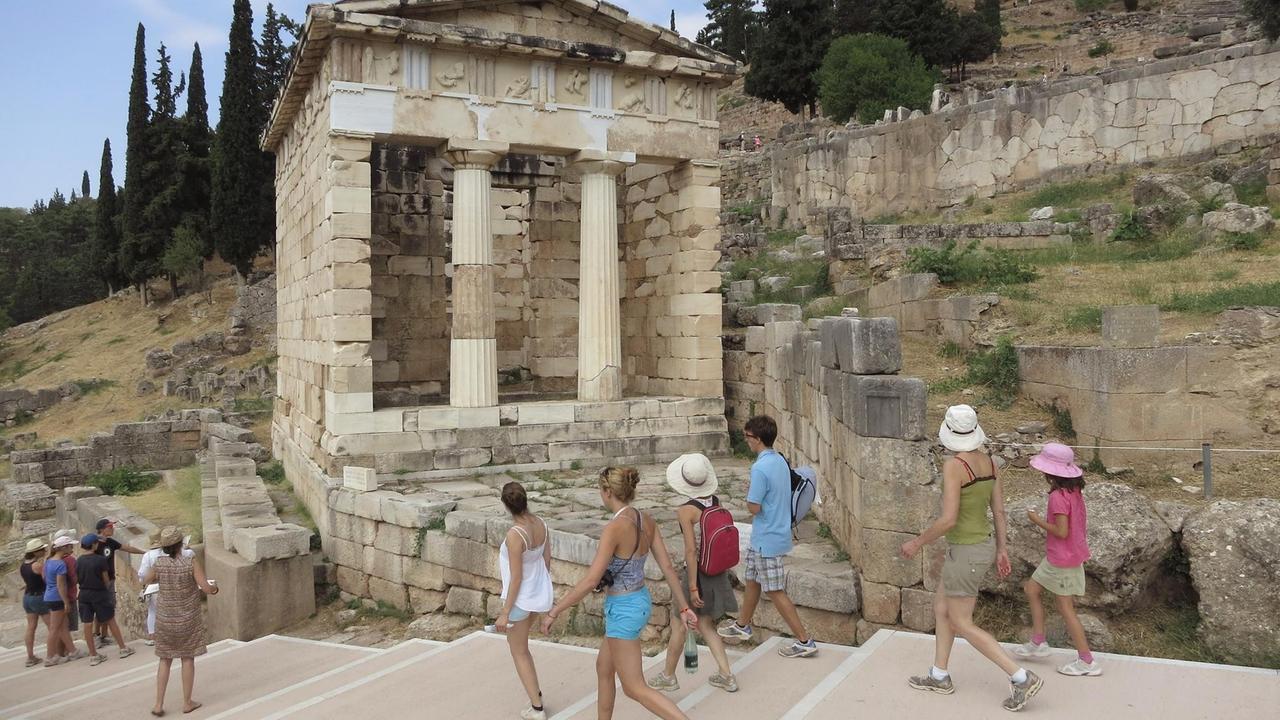 Besucher spazieren durch die ehemalige Schatzkammer der Athener an der alten archäologischen Stätte von Delphi in Griechenland.