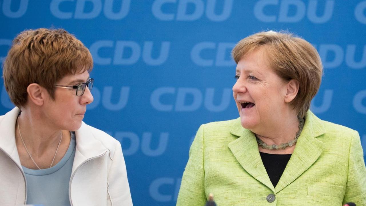 Die saarländische Ministerpräsidentin Kramp-Karrenbauer und CDU-Chefin Merkel blicken sich an.