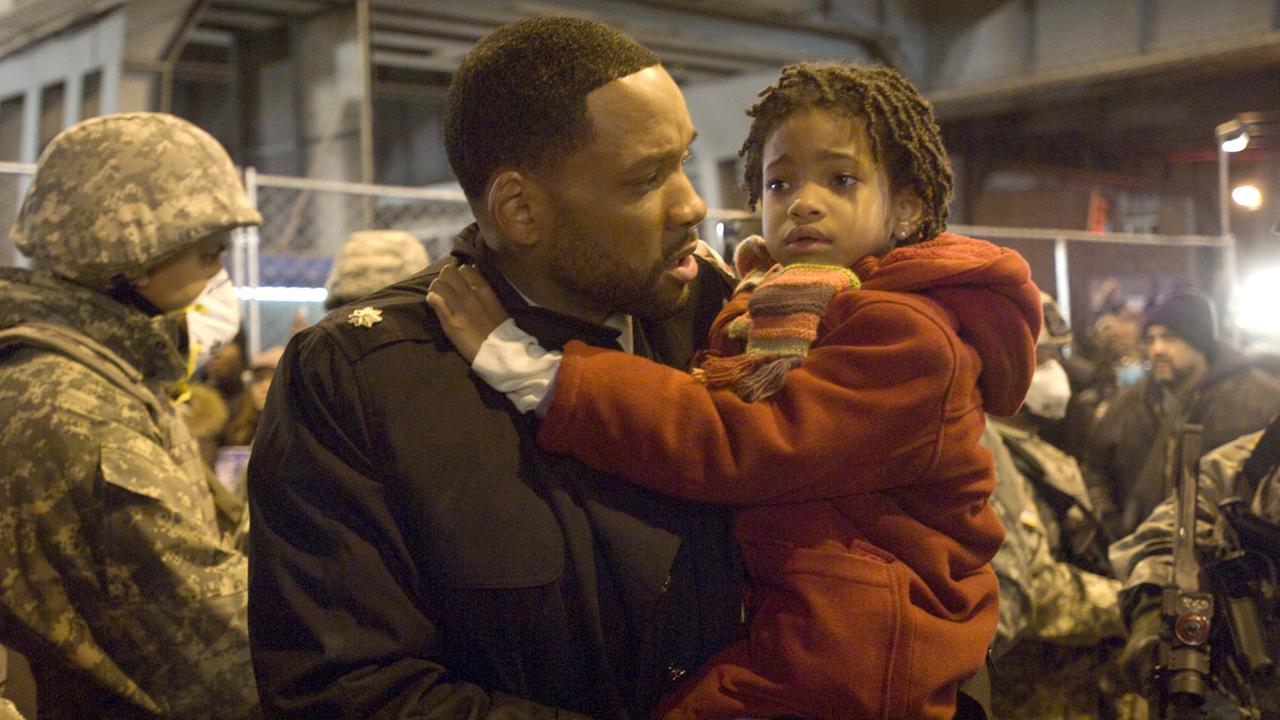 Robert Neville (Will Smith) hält Marley (Willow Smith) auf dem Arm, während im Hintergrund Soldaten mit Atemschutz stehen; undatierte Filmszene aus dem Film "I am Legend" von Robert Neville aus dem Jahr 2007