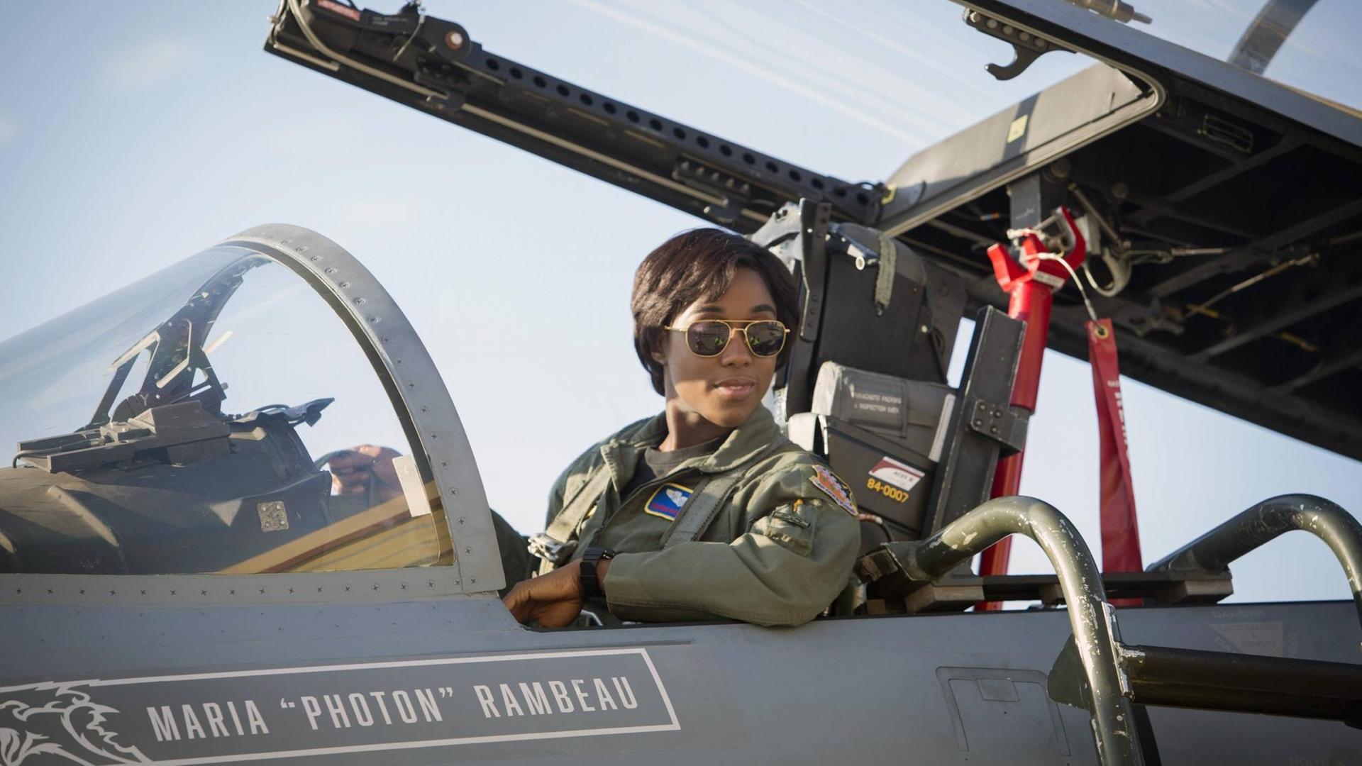 Filmszene von Lashana Lynch als Maria Rambeau in Captain Marvel. Sie sitzt in einem Jagdflugzeug und trägt eine für Piloten typische Sonnenbrille.