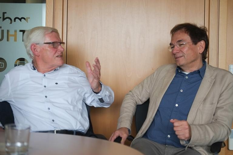 Hilmar Süß und Michael Wenkel, ehemals Redakteure im Sender Weimar des Rundfunks der DDR, sitzen an einem Tisch und unterhalten sich.