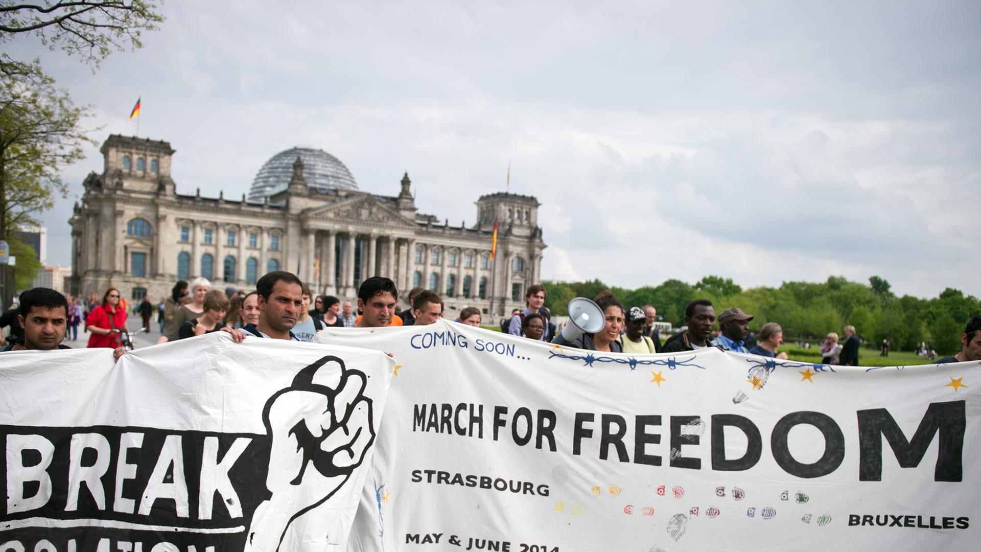 Flüchtlinge halten in Berlin bei einer Demonstration vor dem Reichstag ein Banner mit den Schriftzügen "Break Isolation" und "March for Freedom".