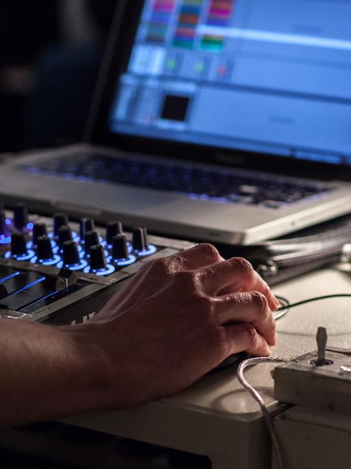 Ein Soundkünstler arbeitet mit Mischpult und Computer.
