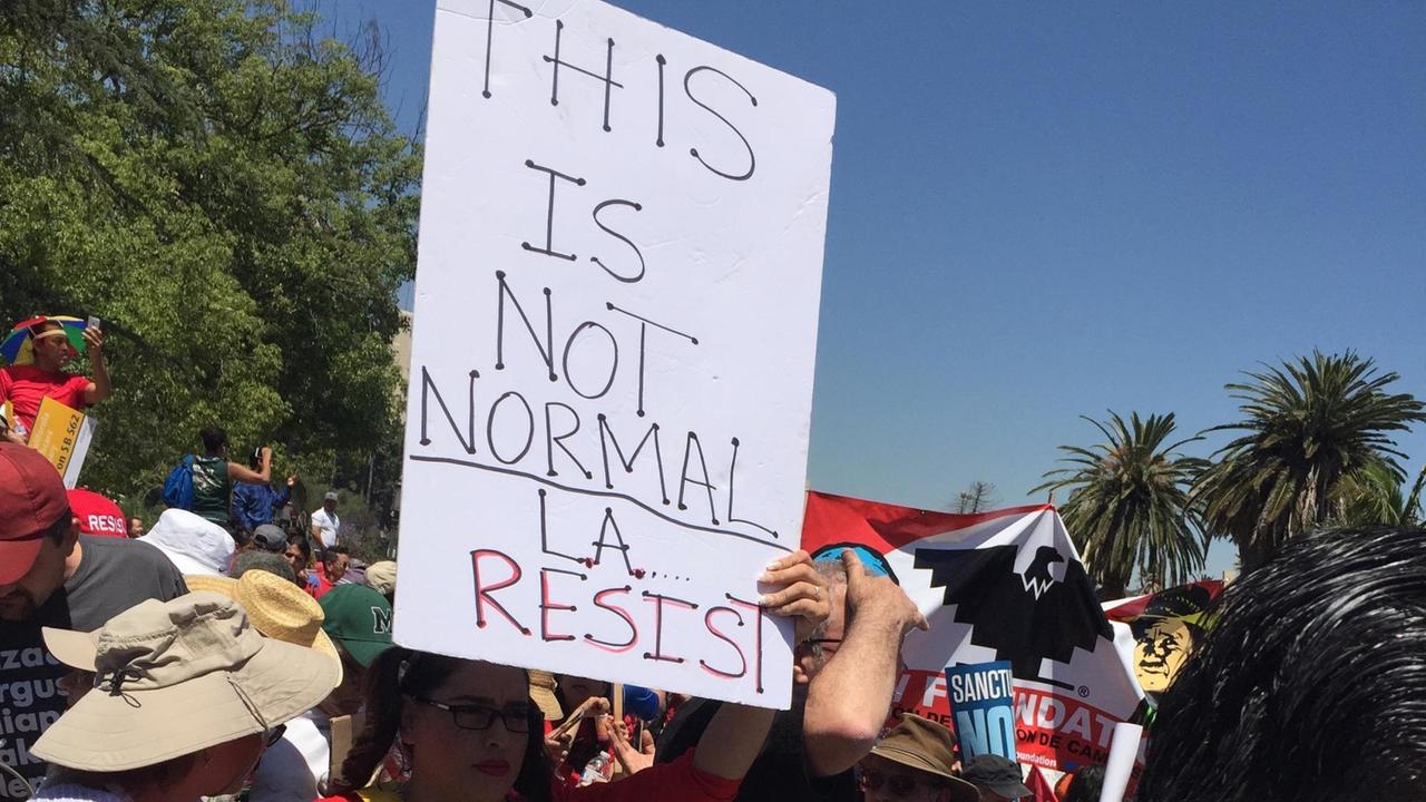 Eine Demonstratin hält auf einer Kundgebung in Los Angeles gegen die Politik von US-Präsident Donald Trump ein Plakast in die Höhe.