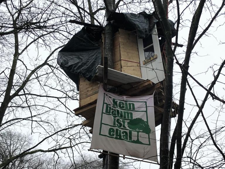 Ein Baumhaus mit einem Transparent mit der Aufschrift "Kein Baum ist egal"