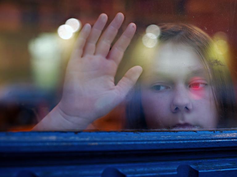 Ein junges Mädchen blickt am 24.01.2014 in Berlin aus einem Fenster.