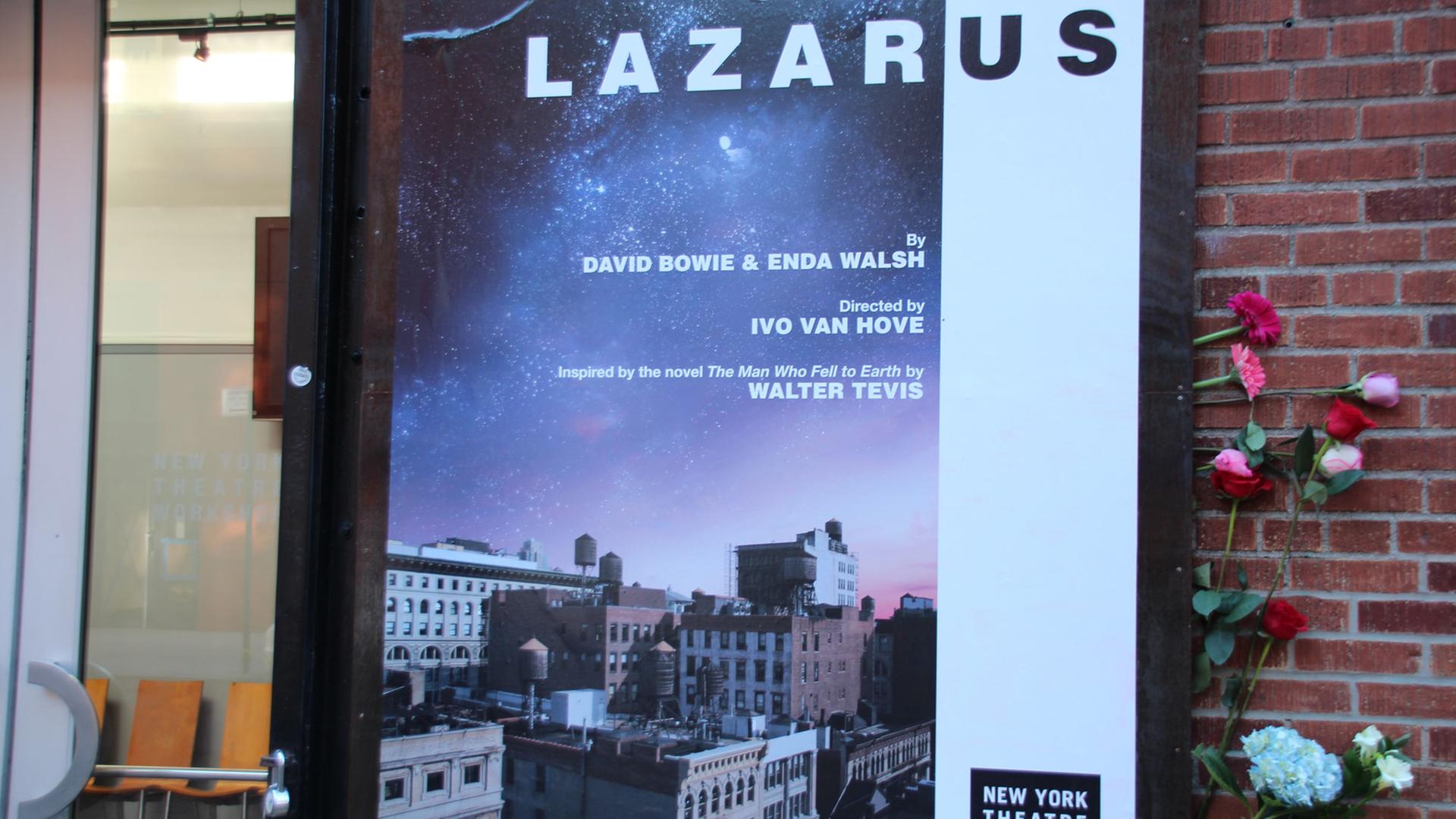 Blumen, im Gedenken an den verstorbenen britischen Musiker David Bowie, stecken in New York an einem Plakat, das am Theatre Workshop für das Bowie-Musical "Lazarus" wirbt.