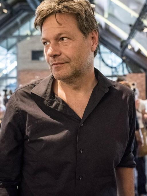 Der Co-Vorsitzende der Grünen, Robert Habeck, bei einer Veranstaltung mit Publikum im Rücken, schaut zur Seite und lächelt
