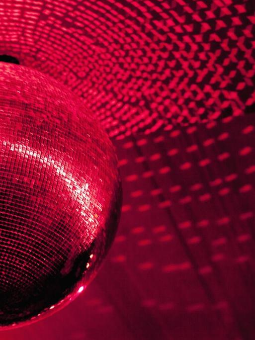 Eine Diskogugel in einem Club wird rot angestrahlt.