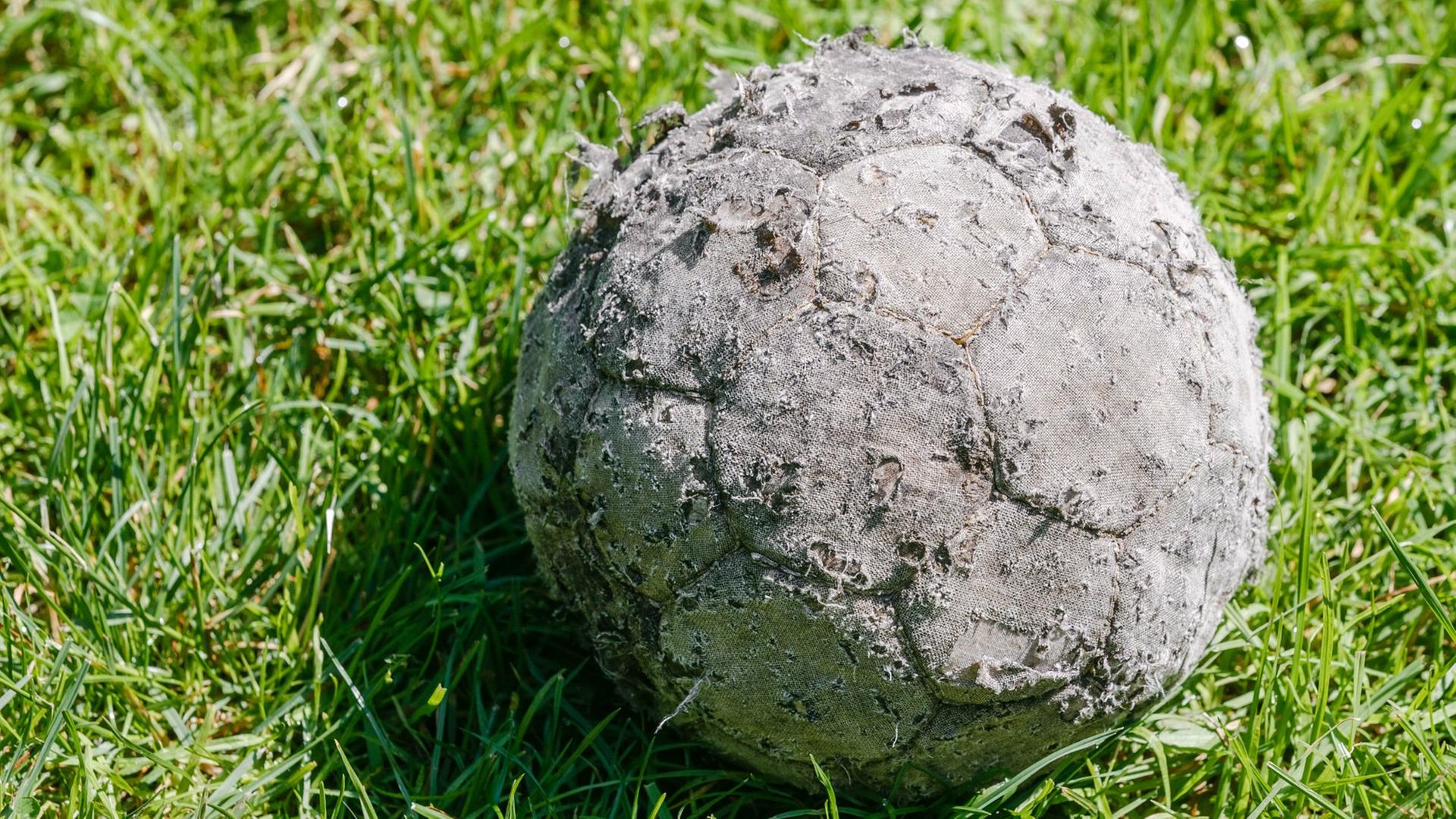 Ein alter verschlissener Fussball liegt am 07.07.2014 in Hamburg auf dem Rasen.