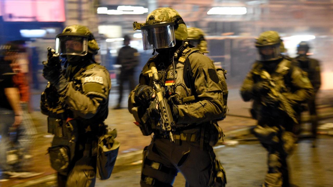 Spezialkräfte der Polizei laufen in Schutzkleidung und Gewehren durch das Schanzenviertel.
