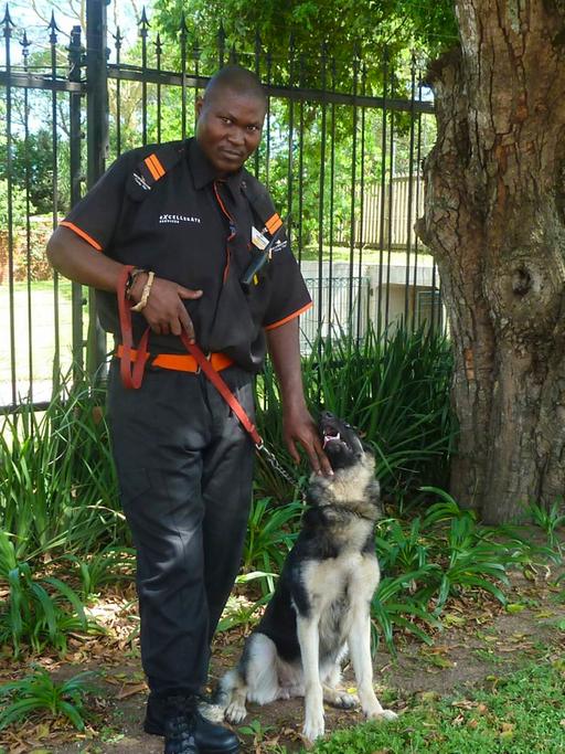 Sibusiso Gumede und sein Hund machen Patrouille am Zaun einer "Gated Community" im südafrikanischen Durban.