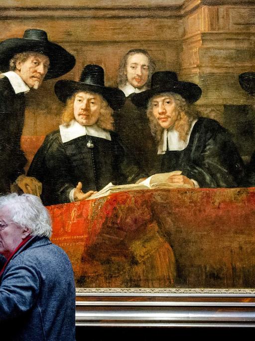 Zwei Männer diskutieren vor Rembrandts "The Steelmasters", das in der Ausstellung "Der späte Rembrandt" im Amsterdamer Reichsmuseum gezeigt wird.