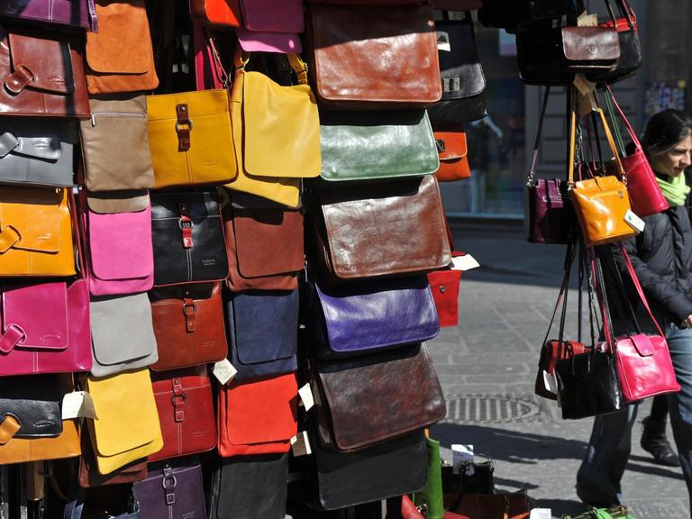 Zwei Frauen gehen am Montag (08.03.2010) in Florenz an einem Stand mit Leder-Handtaschen in verschiedenen Farben vorbei. Foto: Andreas Gebert dpa/lby | Verwendung weltweit