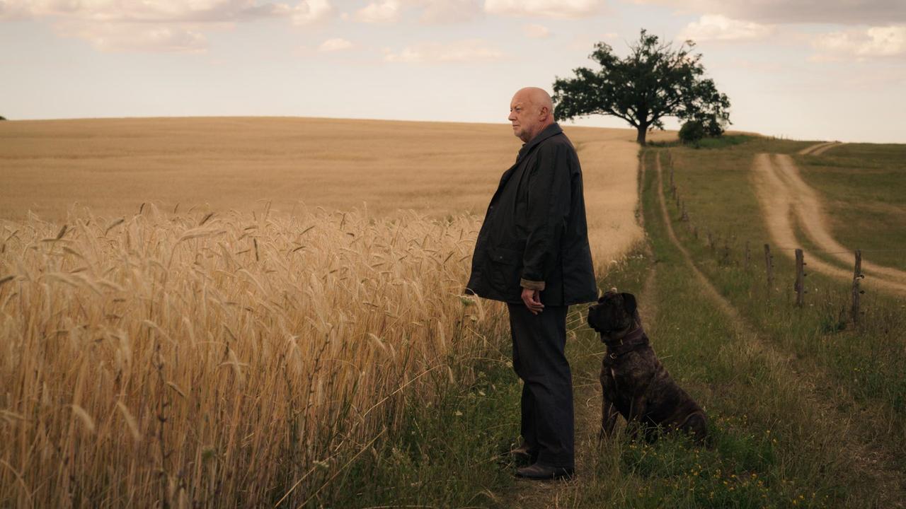 "Unterleuten - Das zerrissene Dorf": Rudolf Gombrowski steht mit seinem Hund vor den Feldern.