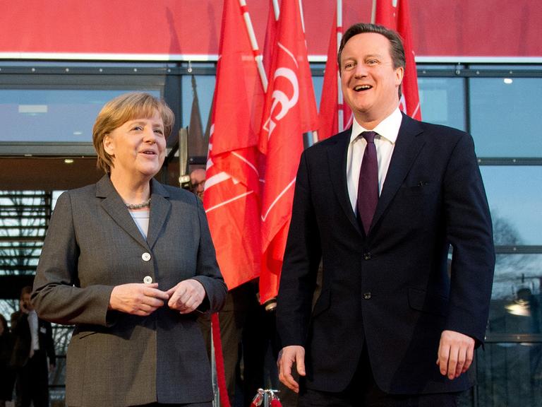 Angela Merkel und David Cameron stehen lächelnd vor roten Flaggen der Computermesse CeBIT in Hannover