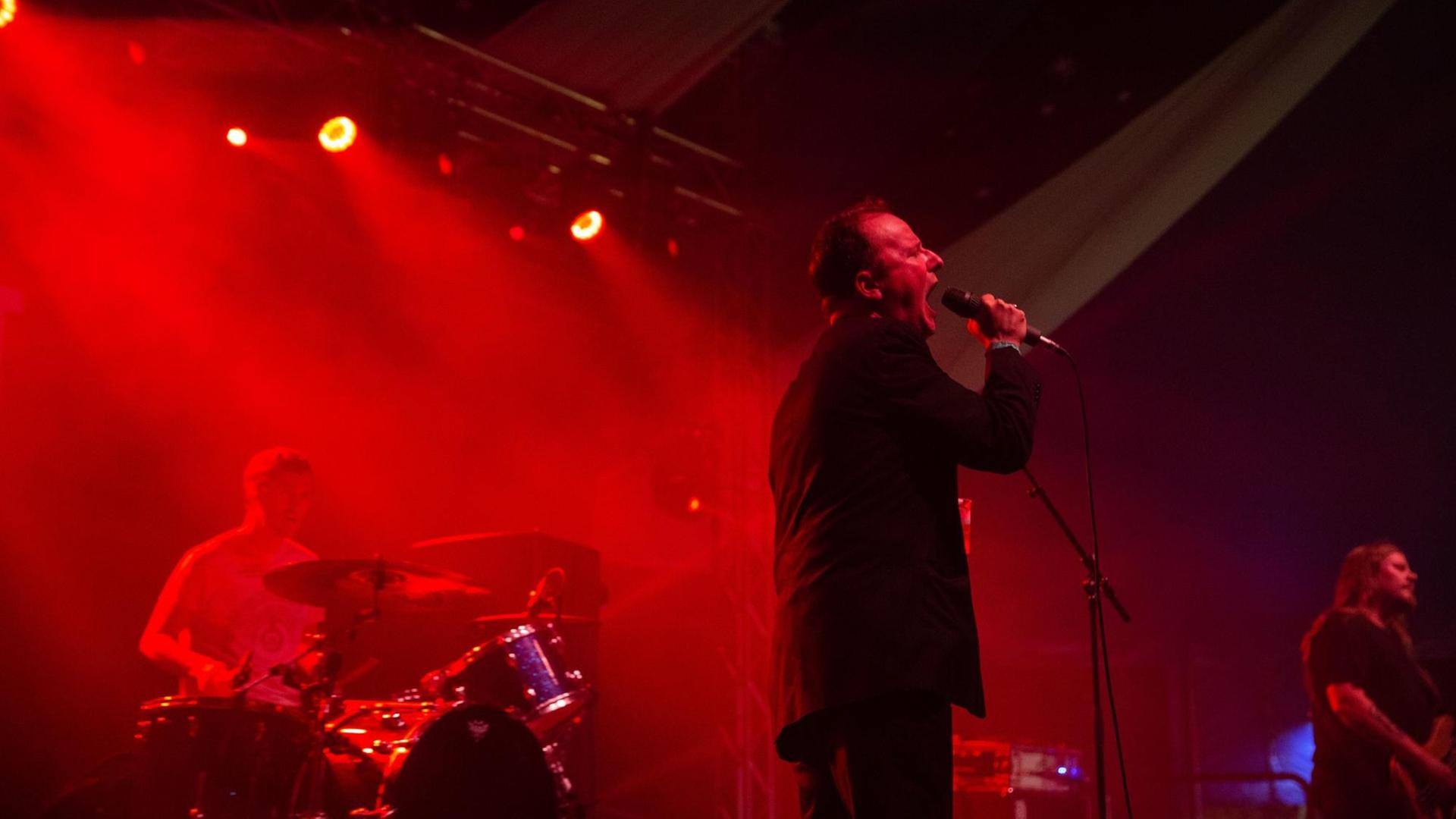 Die US-Band Protomartyr bei einem Konzert im Jahr 2018: Die Bühne ist in rotes Licht getaucht.