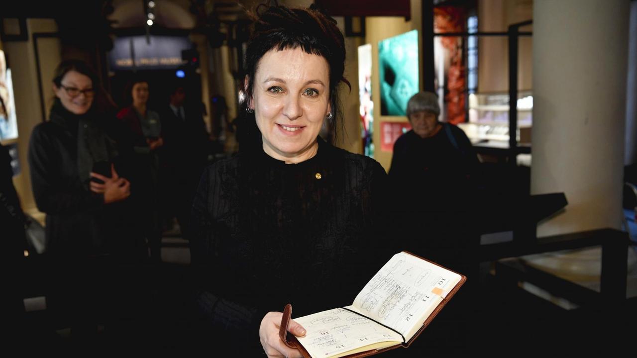 Literaturnobelpreisträgerin Olga Tokarczuk mit einem aufgeschlagenen Wochenkalender in der Hand.