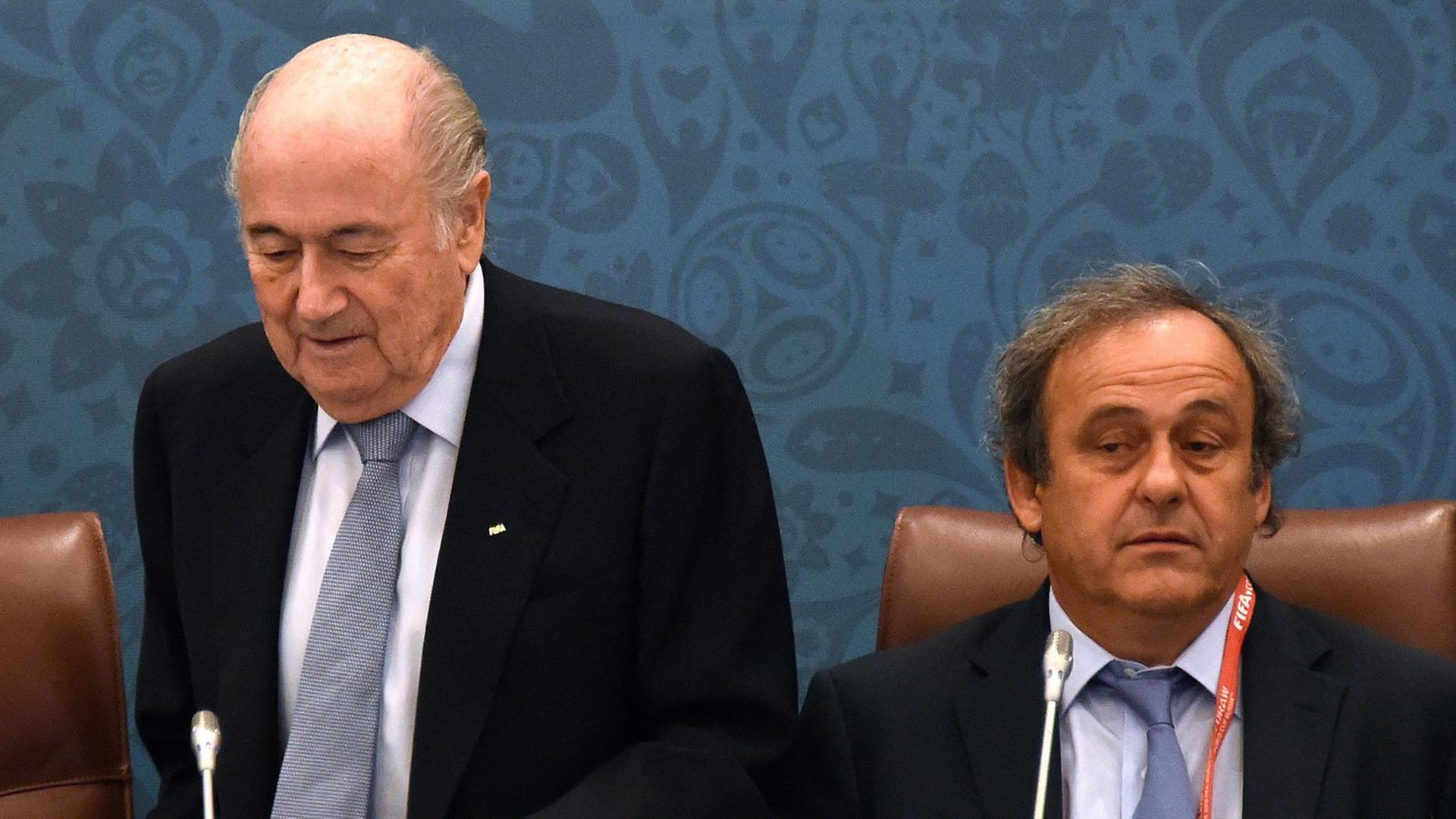 Blatter setzt sich neben Platini. 