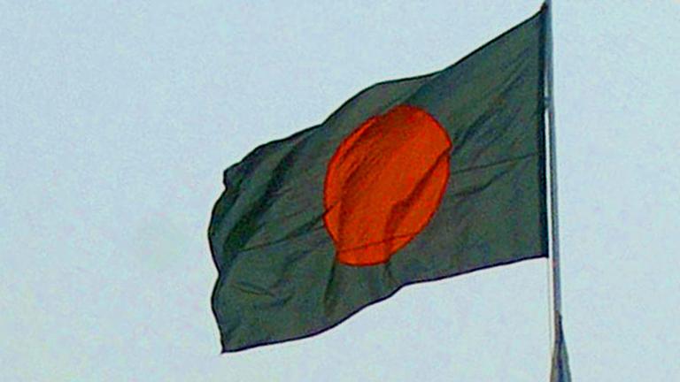 Die Flagge von Bangladesch weht im Wind, sie ist grün mit einem roten Kreis darin.