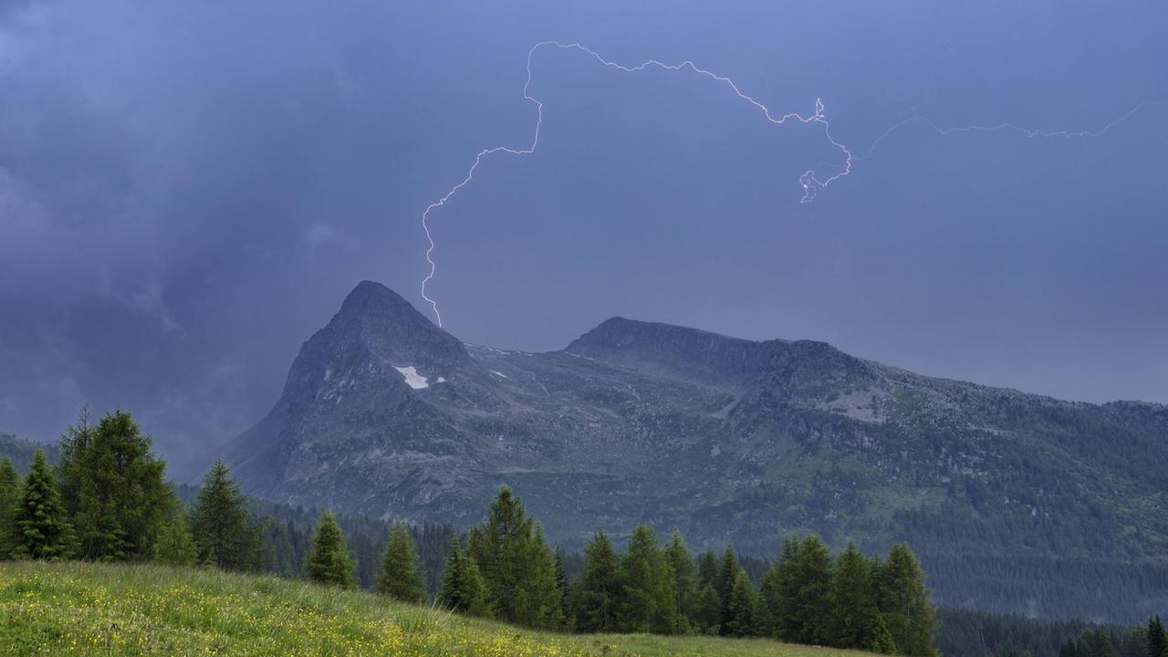 Ein Blitz ist über einem Bergmassiv in den Dolomiten zu sehen.