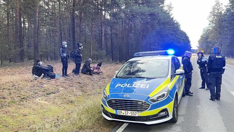 Bundespolizisten stehen neben einer Gruppe von Migranten, die zuvor Mitte Oktober 2021 über die deutsch-polnische Grenze gegangen waren.