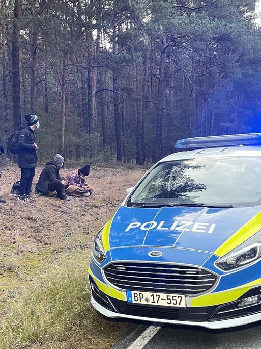 Bundespolizisten stehen neben einer Gruppe von Migranten, die zuvor Mitte Oktober 2021 über die deutsch-polnische Grenze gegangen waren.