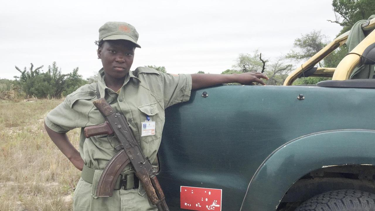 Ein Ranger des Nationalparks Banhine steht an einem Pickup mit einem Sturmgewehr vor der Brust.