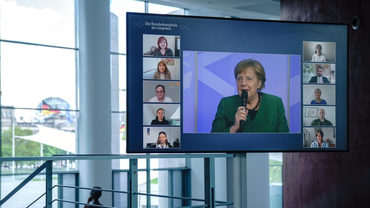 Bundeskanzlerin Angela Merkel ist bei der digitalen Dialogreihe "Die Bundeskanzlerin im Gespräch" mit ehrenamtlichen Helfern auf einem Bildschirm im Bundeskanzleramt zu sehen.