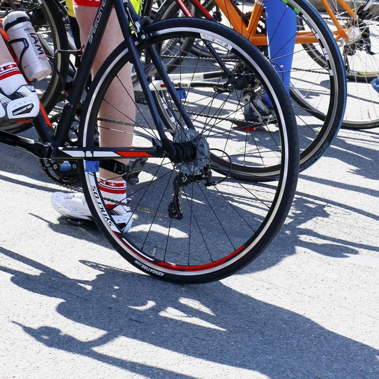 Bei einem Radsport-Straßenrennen stehen mehrere Fahrer mit ihren Rädern nebeneinander.