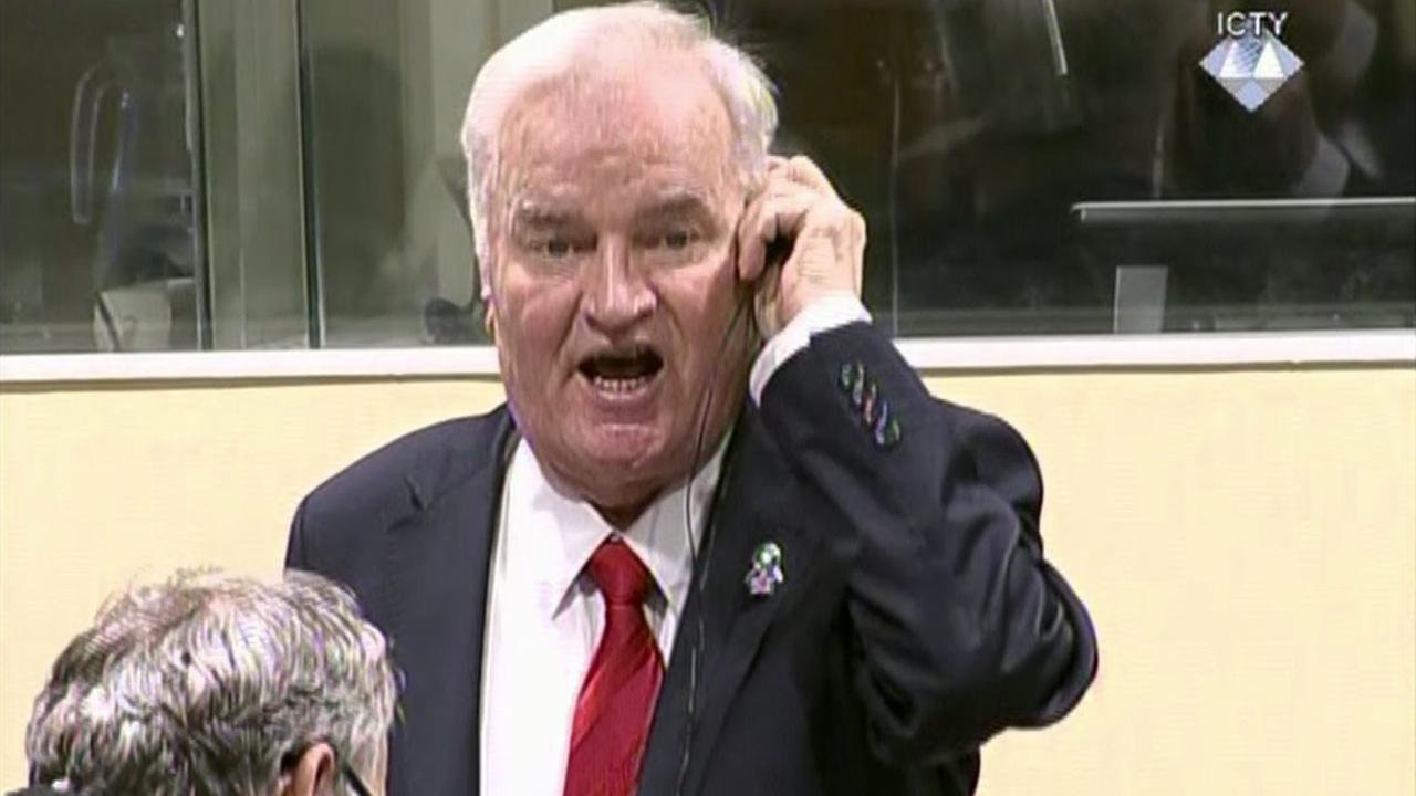 Mladic hat eine Hand am Kopfhörer und schimpft.