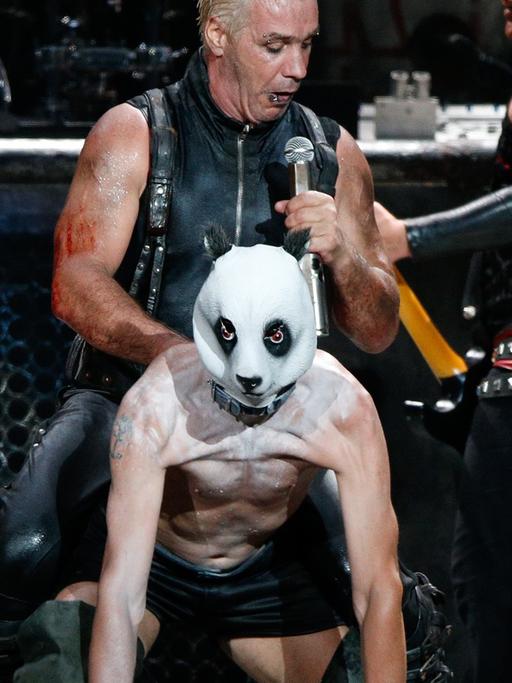 Till Lindemann, Sänger der Band Rammstein sitzt beim Wacken Open-Air Festival auf dem Keyboarder der Band, Flake Lorenz, der sich eine Panda-Maske aufgesetzt hat