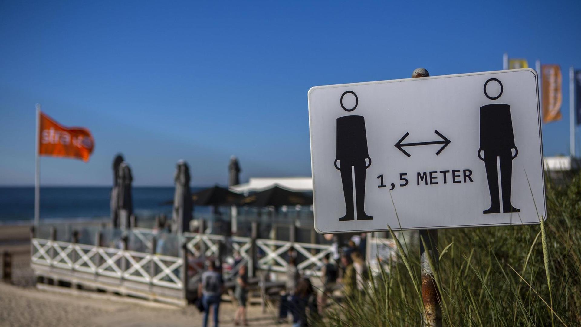 Ein Schild am Strand, das 1,5 Meter Abstand fordert
