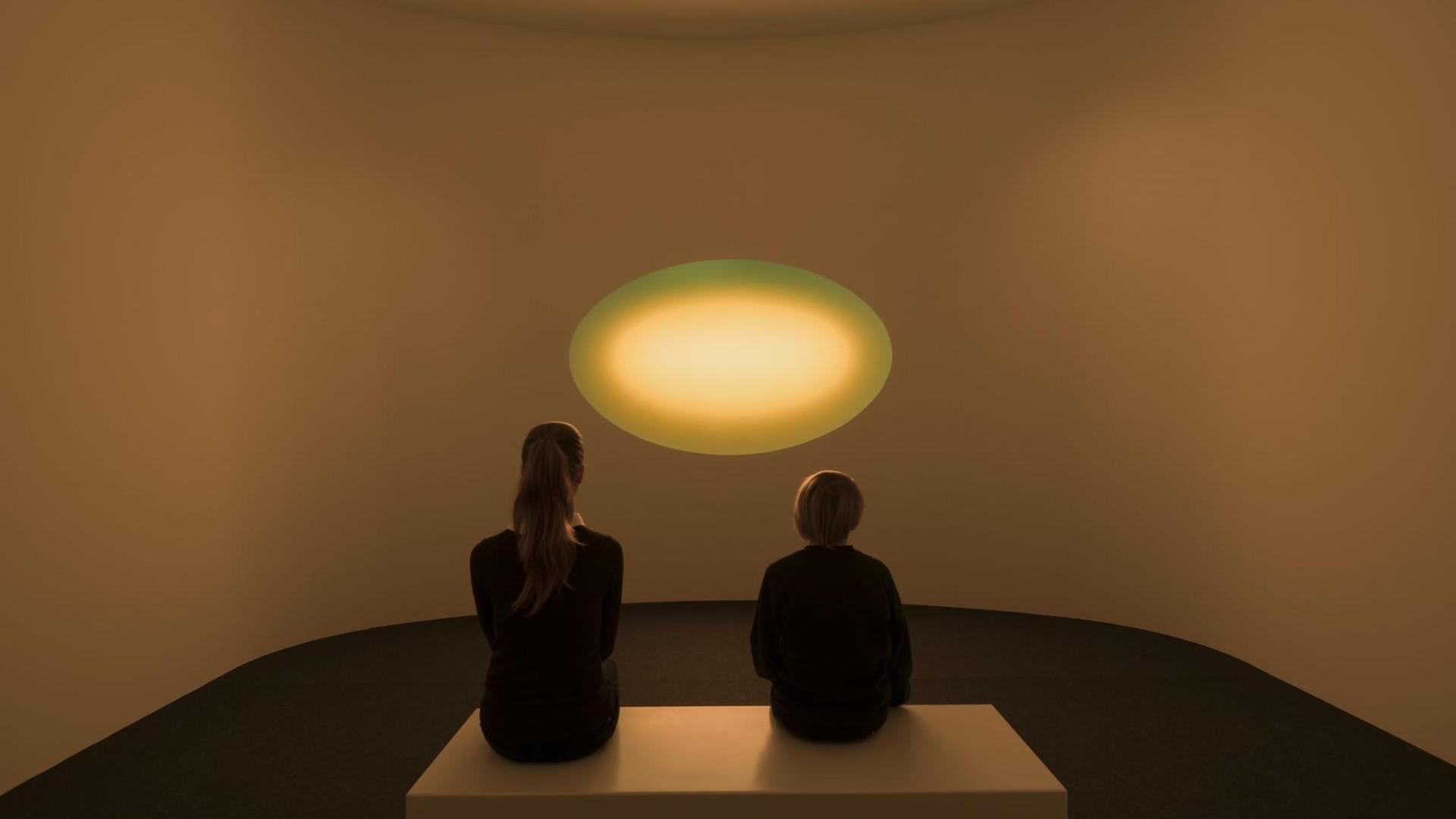 Zwei Ausstellungsbesucher sitzen vor dem Werk "Curved Wide Glass" von James Turrell im Museum Frieder Burda in Baden-Baden