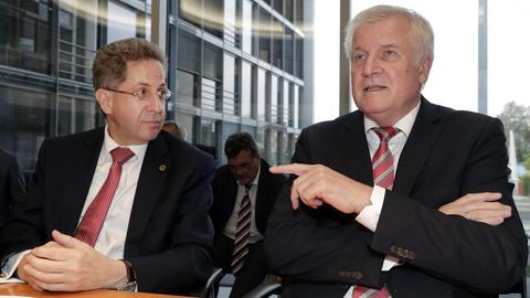 Maassen sitzt neben Seehofer vor einer Fensterfront. AP Photo/Michael Sohn)