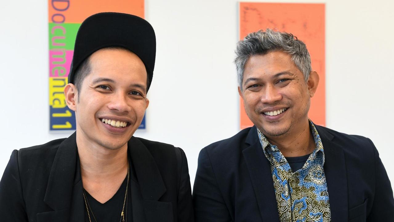 Die beiden Vertreter des indonesischen Künstlerkollektivs Ruangrupa, das die documenta 15 kuratieren wird, Farid Rakun (links) und Ade Darmawan, lächeln in Richtung der Kamera.