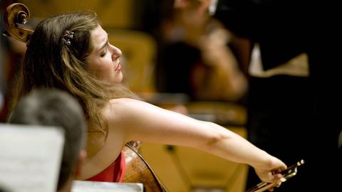 Eine junge Frau, von der Seite betrachtet, spielt mit viel Einsatz auf ihrem Cello.