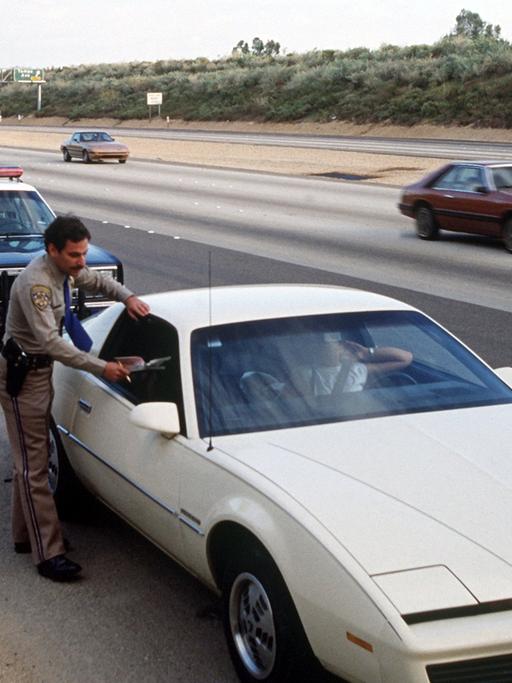Ein Polizist der California Highway Patrol gibt einem Verkehrssünder im Auto einen Strafzettel.
