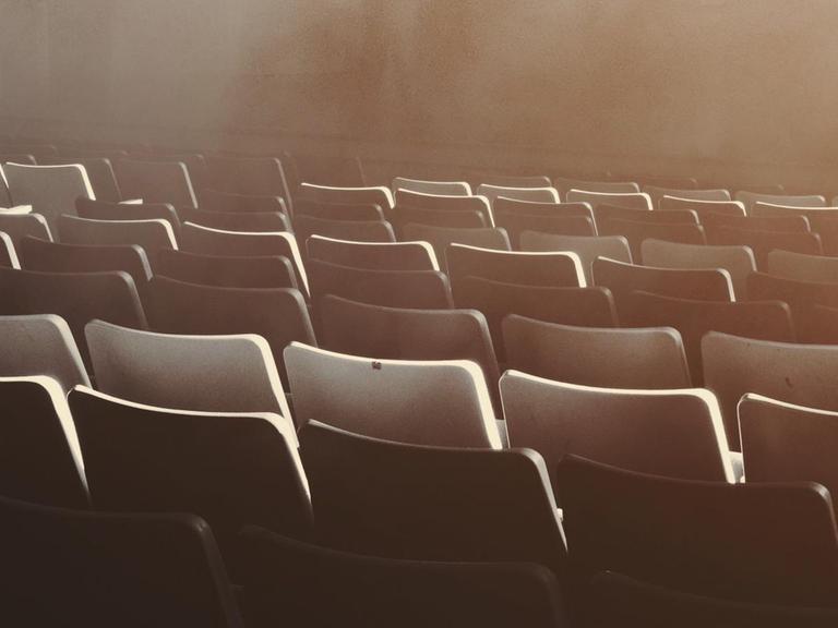 Eine farbmonochrome Aufnahme mehrerer Stuhlreihen von Nebel umgeben.