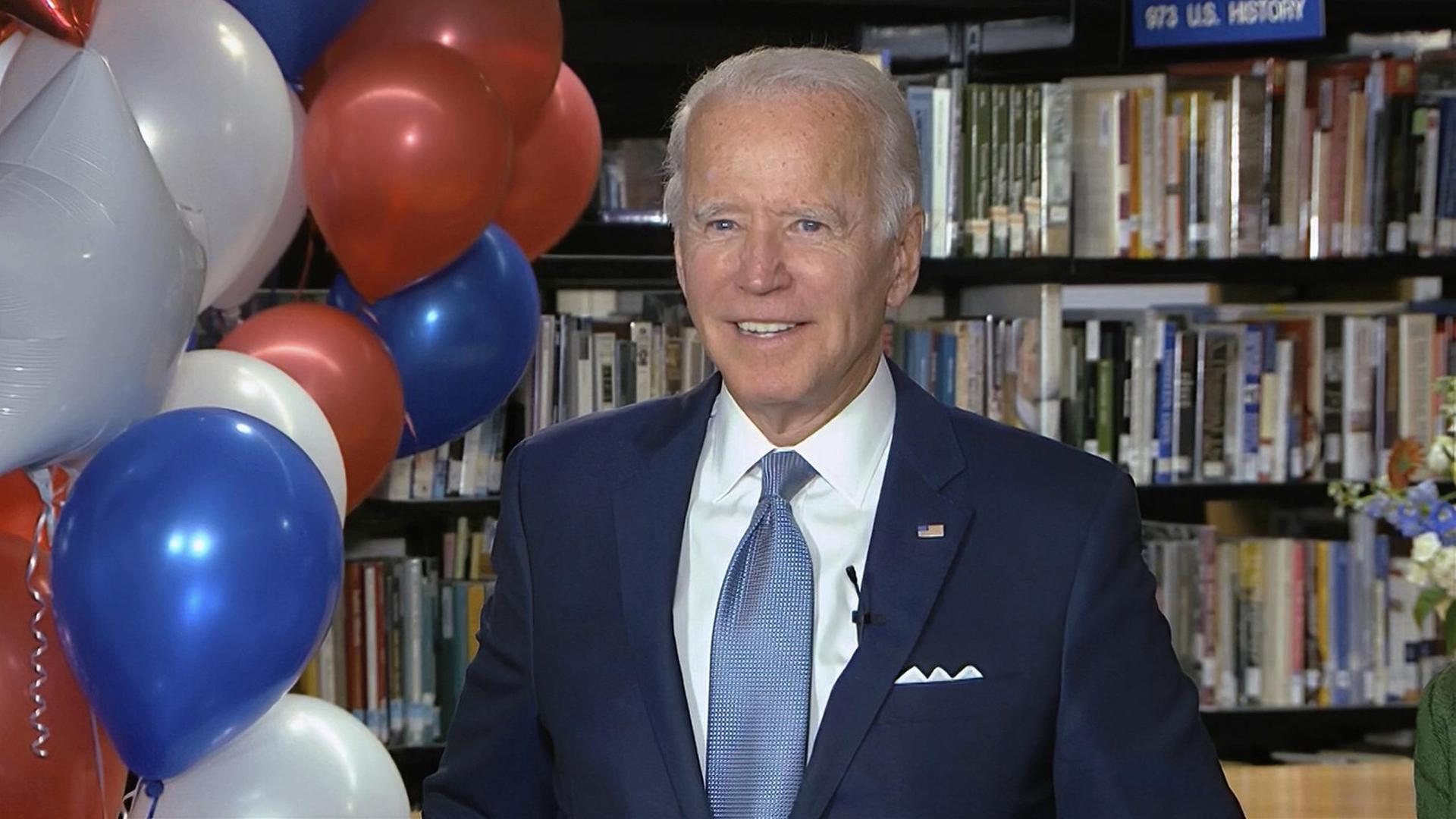 Joe Biden, Präsidentschaftskandidat der Demokraten, im Anzug nach seiner Nominierung während eines Parteitages. Neben ihm sind blaue, weiße und rote Luftballons zu sehen.