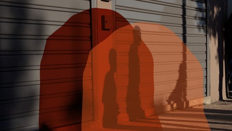 Cover zum Podcast "Feature": Die Schatten von drei Personen auf geschlossenen Fensterläden 