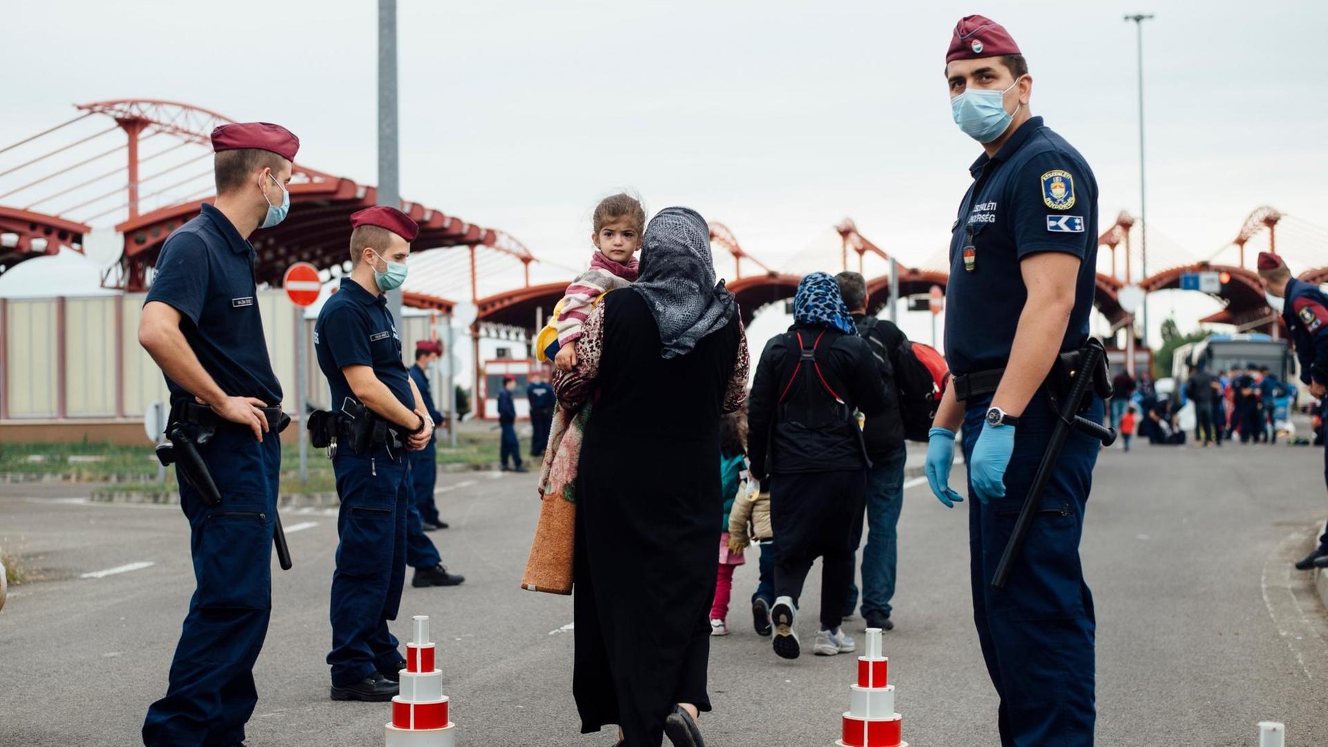 Mehrere Frauen überqueren die Grenze, zu beiden Seiten Grenzschützer.