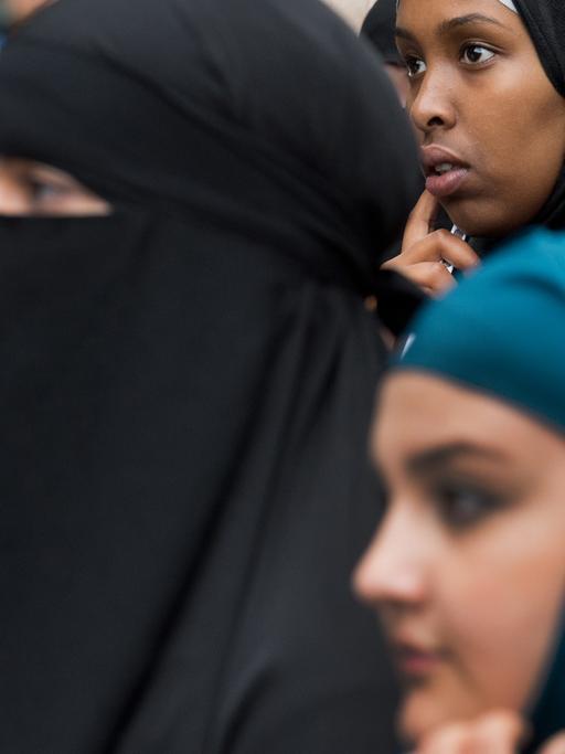 Frauen mit Kopftuch oder Niqab verfolgen eine Kundgebung eines radikalen Salafistenpredigers.