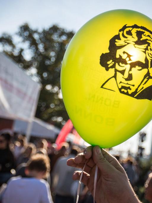 Das Konterfei von Ludwig van Beethoven auf einem Luftballon wird gegen die Sonne gehalten.