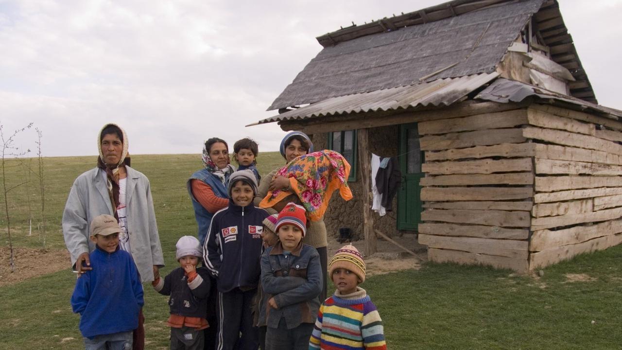 Eine Roma-Familie vor einer Holzhütte