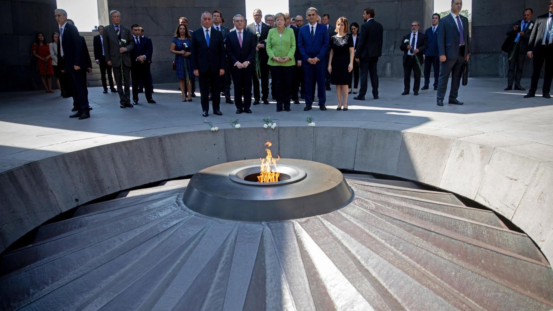 Merkel steht mit weiteren Personen in der Gedenkstätte Tsitsernakaberd in Armenien.