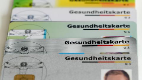 Gesundheitskarten verschiedener Krankenkassen liegen auf einem Tisch
