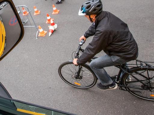 Ein Fahrradfahrer fährt während einer Demonstration des neuen Abbiegeassistenten neben einem Lastwagen.